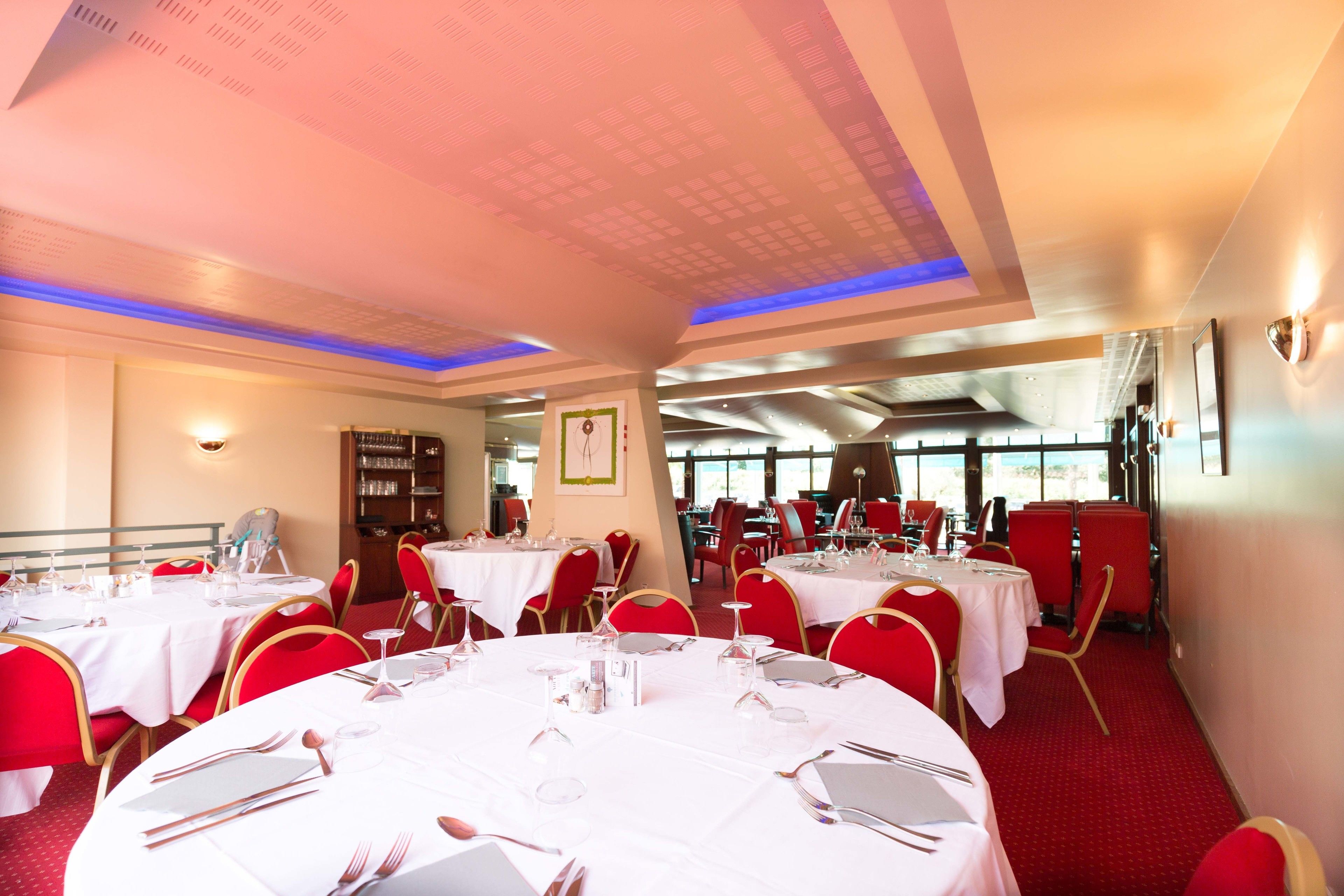 Ein Restaurant mit runden Tischen, roten Stühlen und einem roten Teppich.