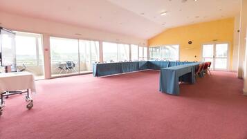 A conference room with a long table, chairs, and a carpeted floor.