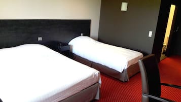 A hotel room with two single beds, a dark headboard, and a red carpeted floor.