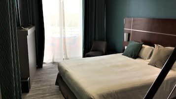 A hotel room with a bed, a chair, a desk, and a view of the outdoors.