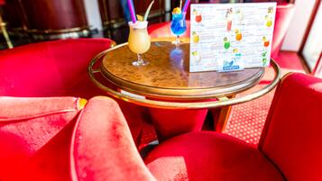 A round table with a menu, two drinks, and red upholstered chairs.