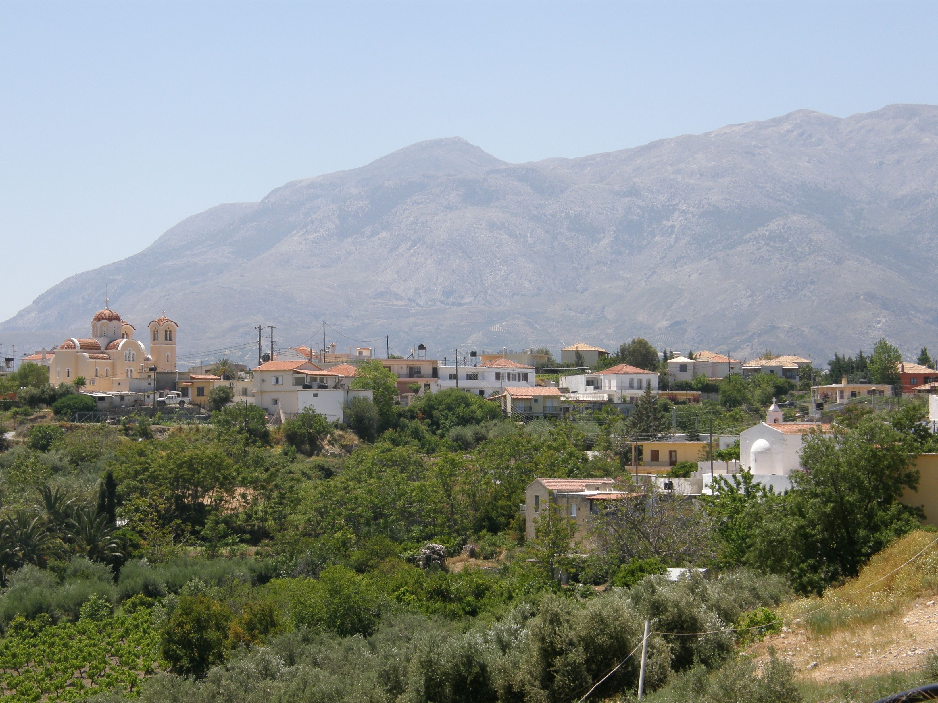 A residential area with houses, a church, and mountains in the background.