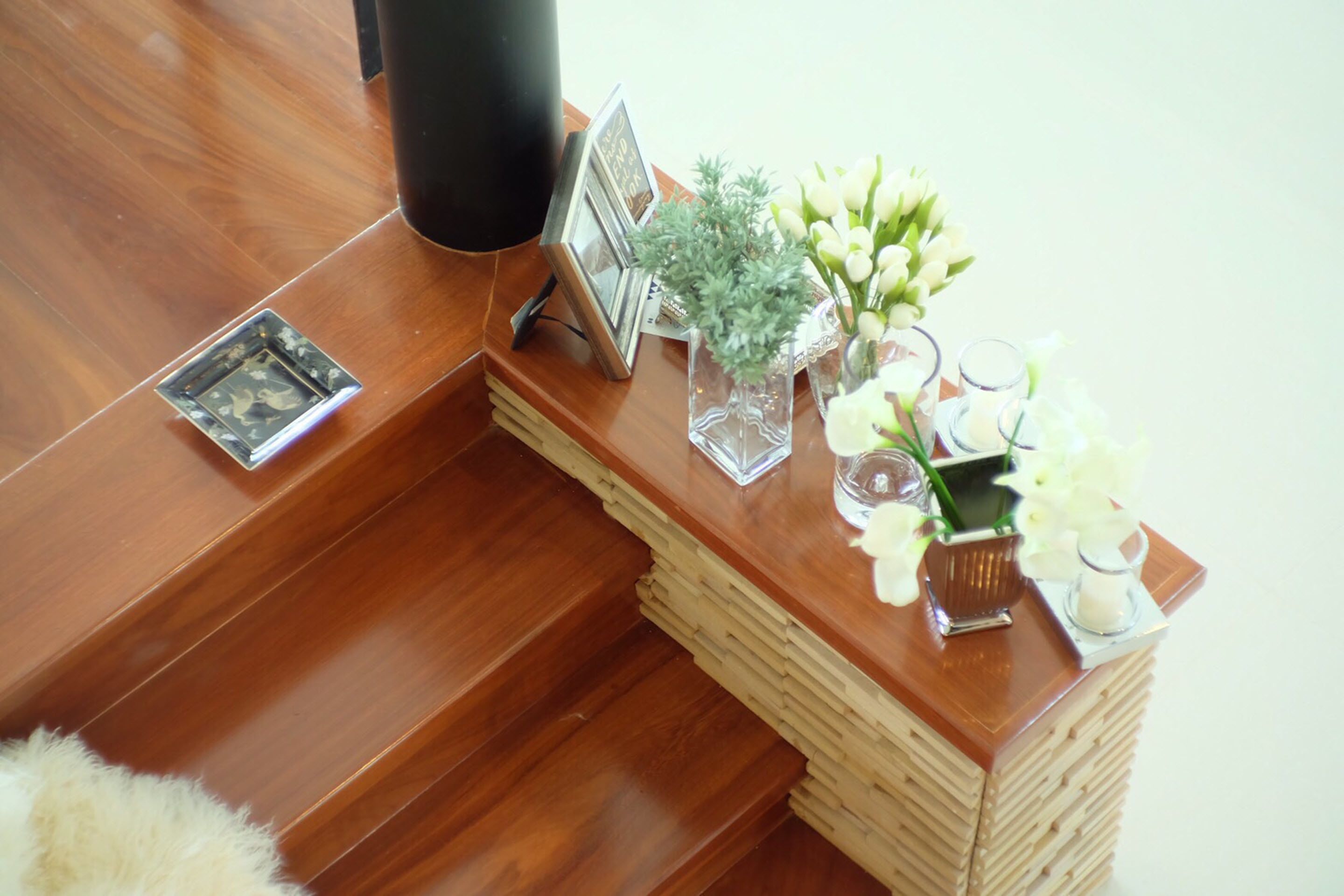 Um balcão de atendimento de madeira com uma planta pequena, quadros e um castiçal.