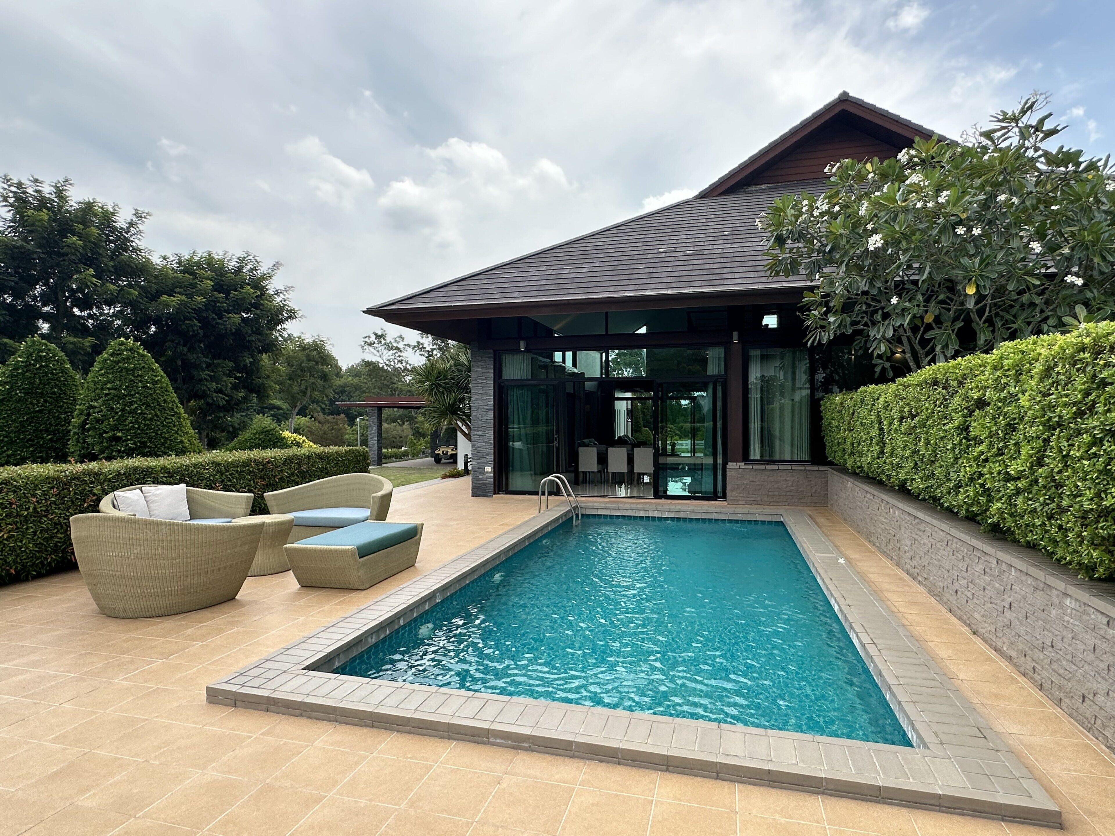 A modern house with a swimming pool, outdoor furniture, and well-maintained landscaping.