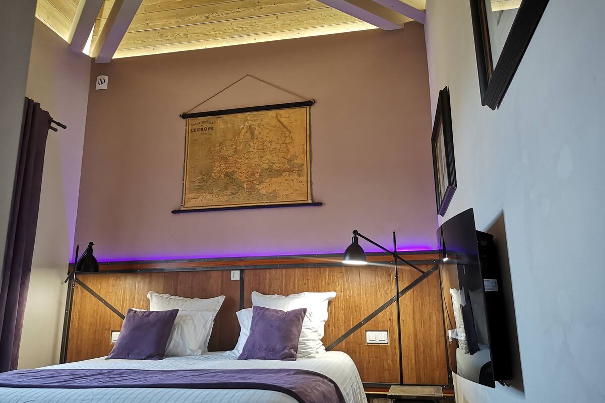 Quarto com cama, um mapa na parede e uma luminária de mesa.