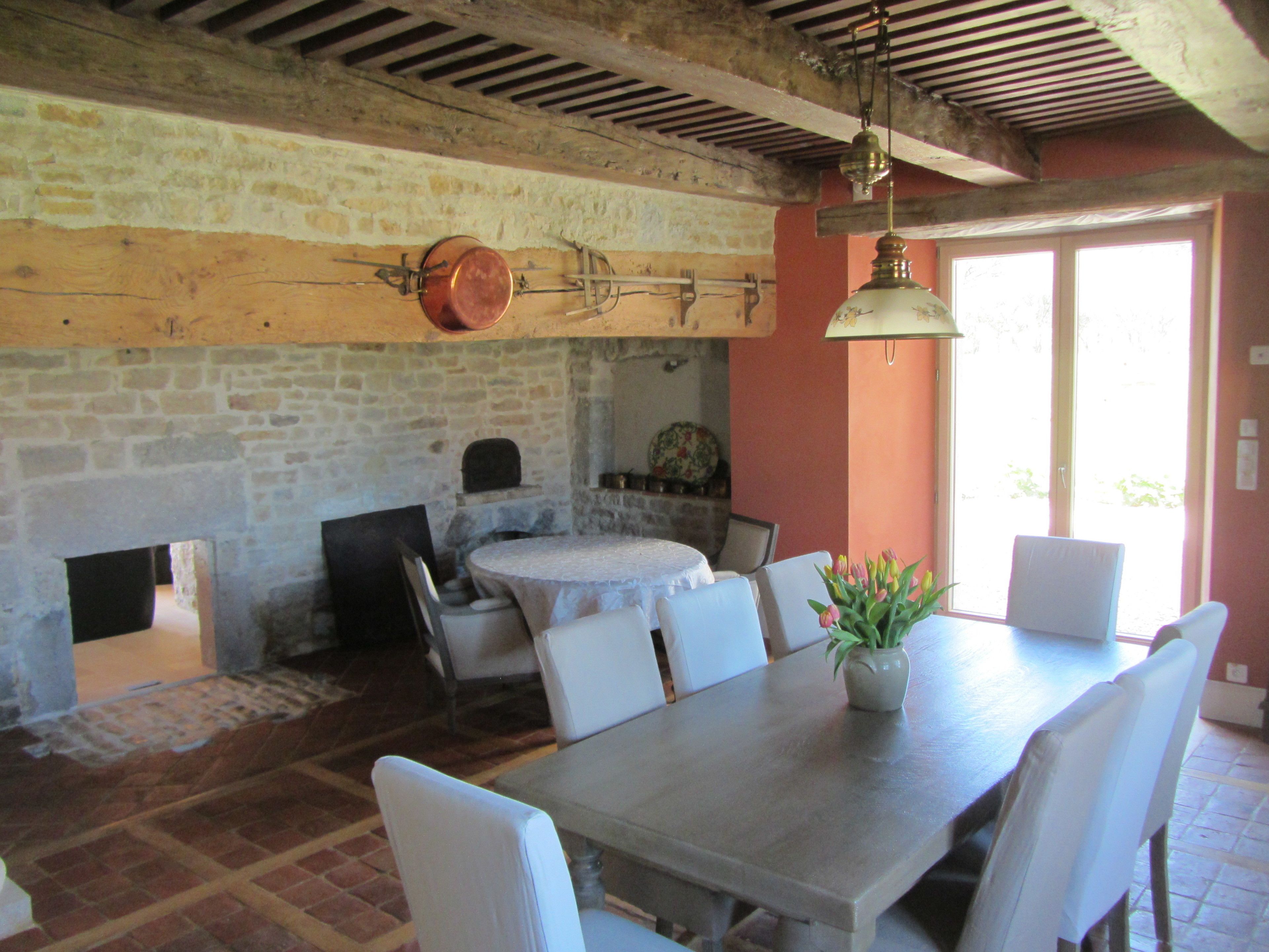 A rustic dining area with a stone wall, a fireplace, and a table set for dining.