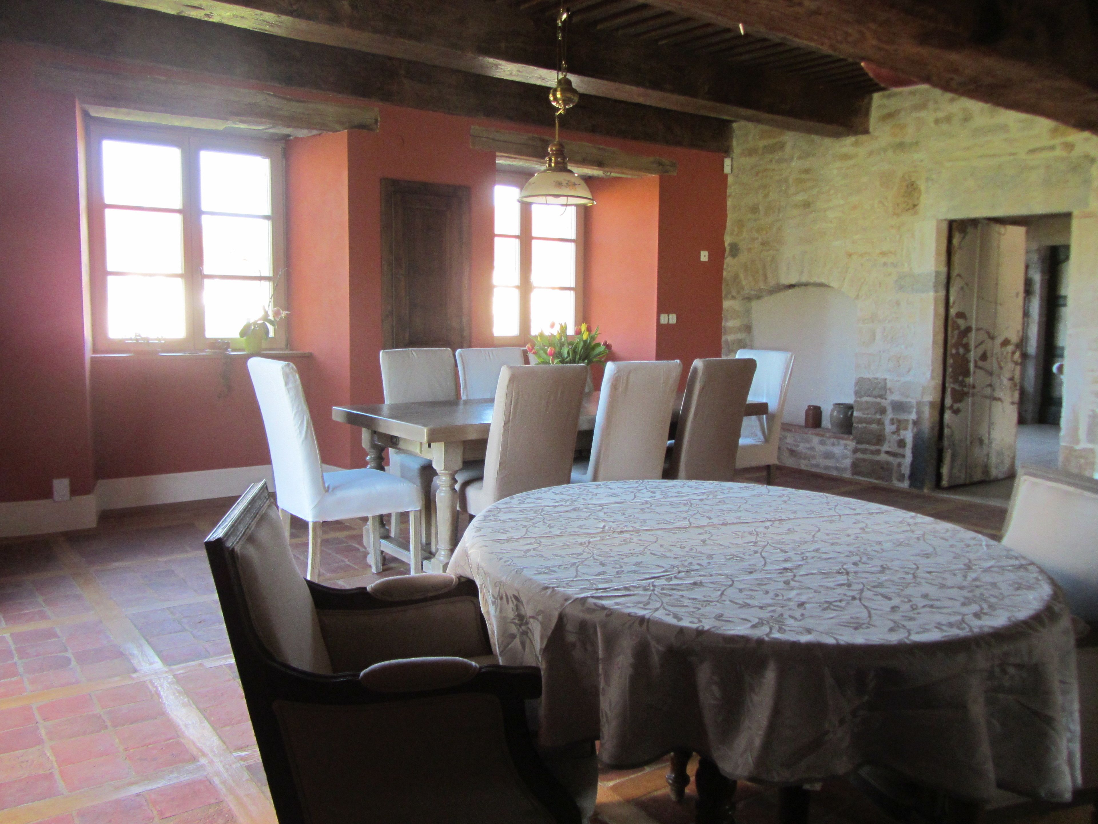 A dining area with a round table, six chairs, and a chandelier.