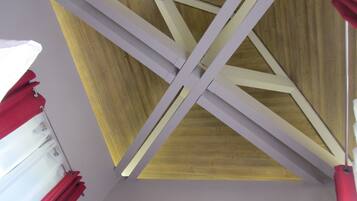 Una habitación con techo inclinado, vigas de madera y una lámpara.