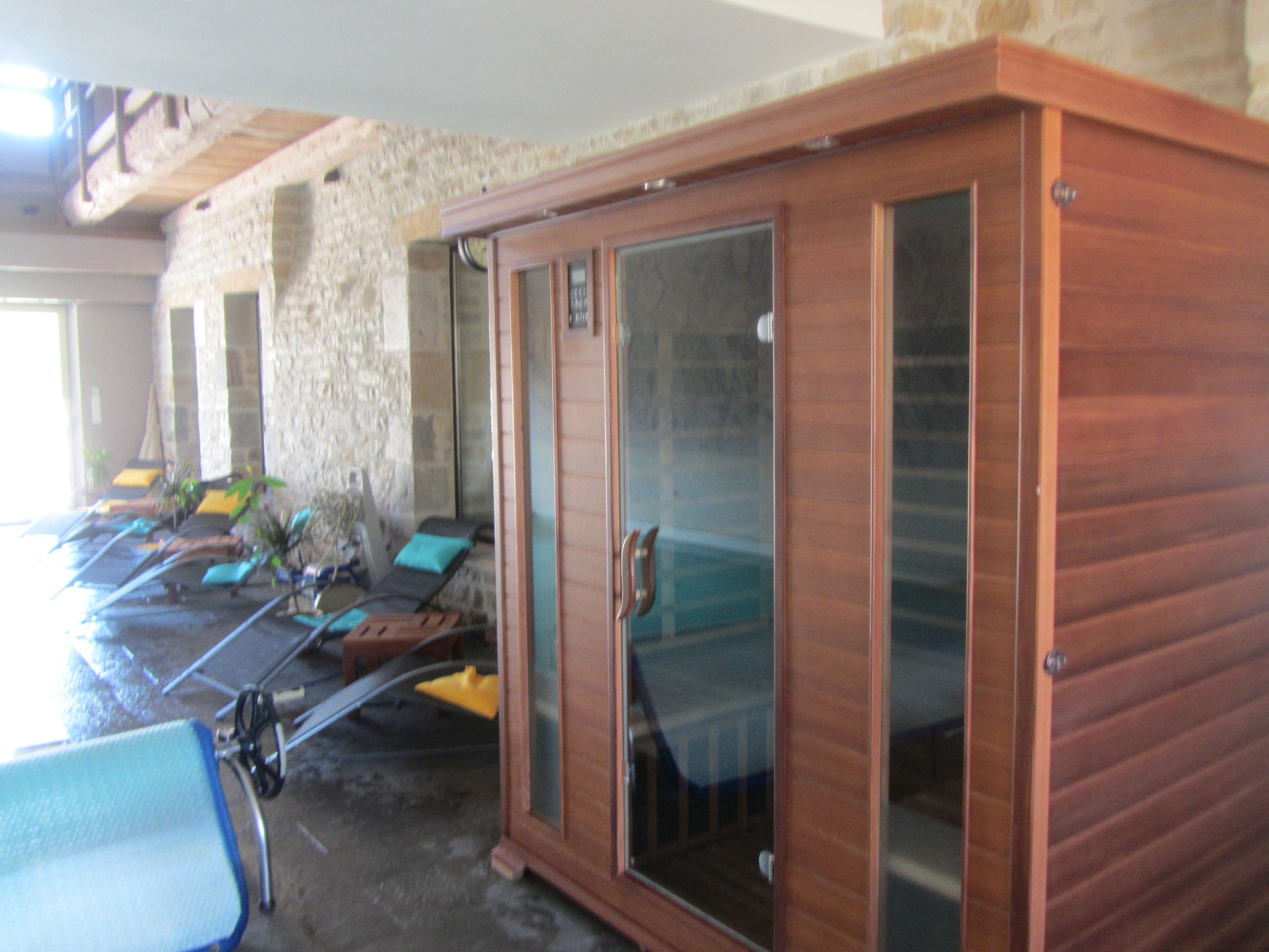 Una habitación con un armario de madera, una pared de piedra y una zona de piscina con sillones de descanso.