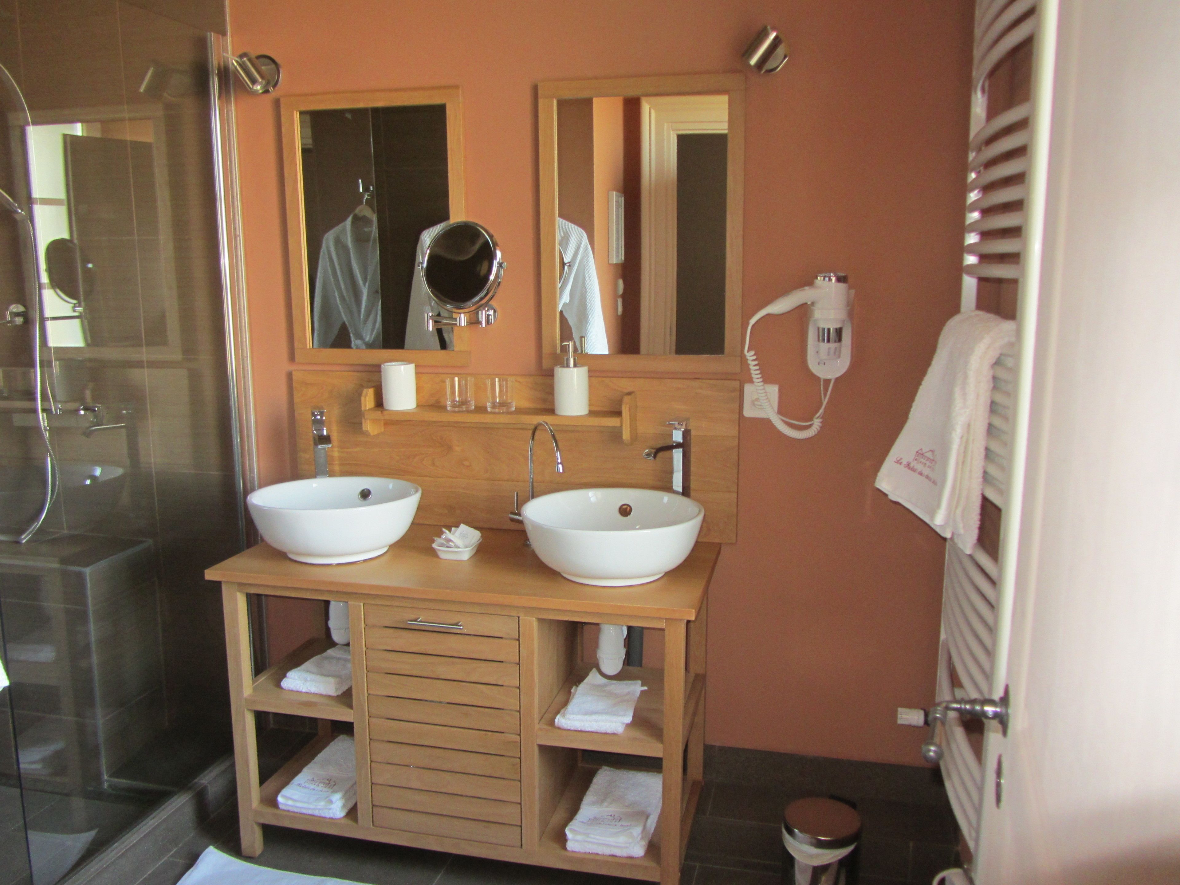 Ein Badezimmer mit zwei Waschbecken, einem Spiegel, einem Handtuchhalter und einer Dusche.