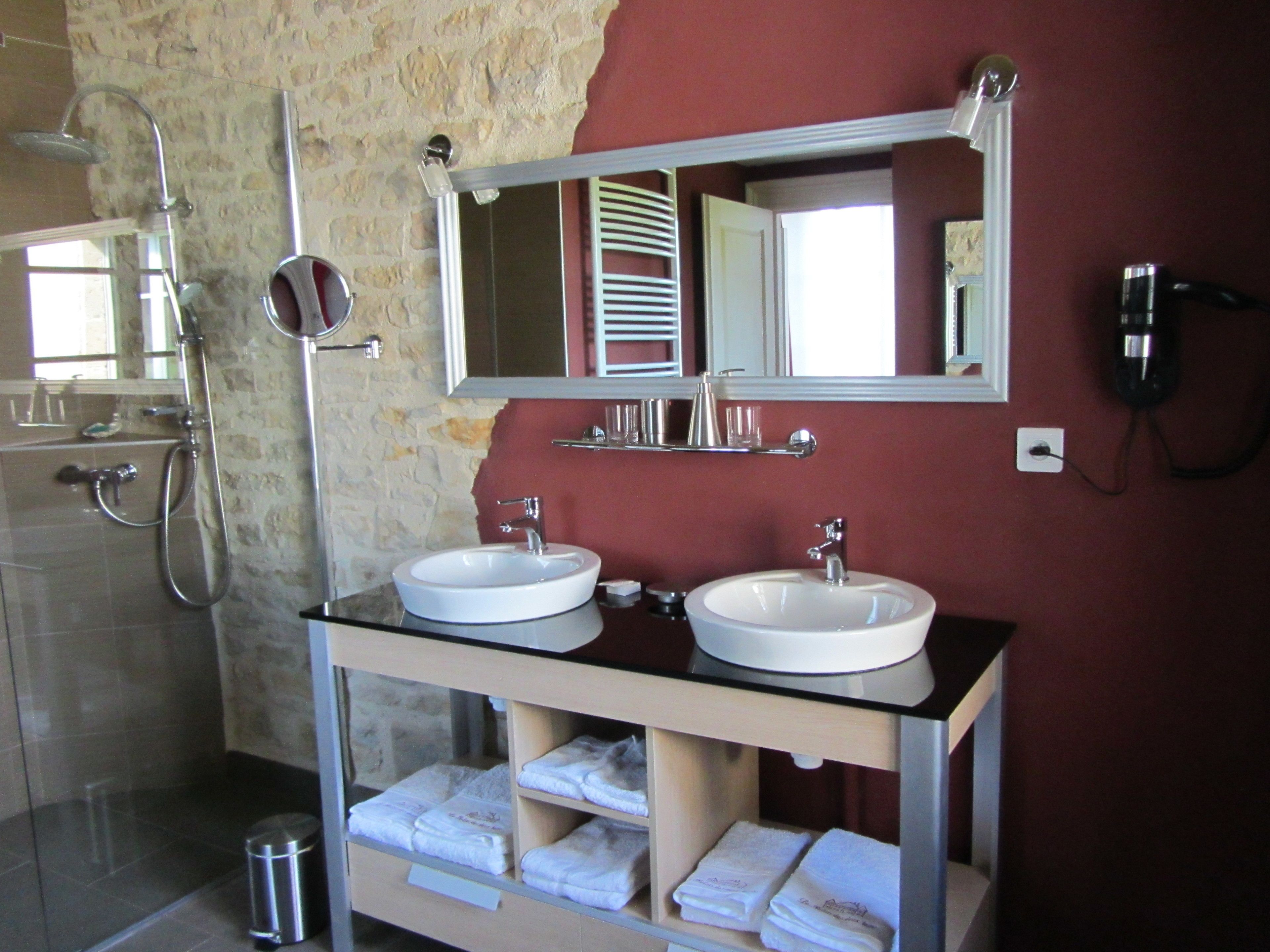 A bathroom with two sinks, a shower, and a mirror.