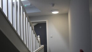 A staircase with white balusters leading to a door marked with the number 10. - Guest House London (London)