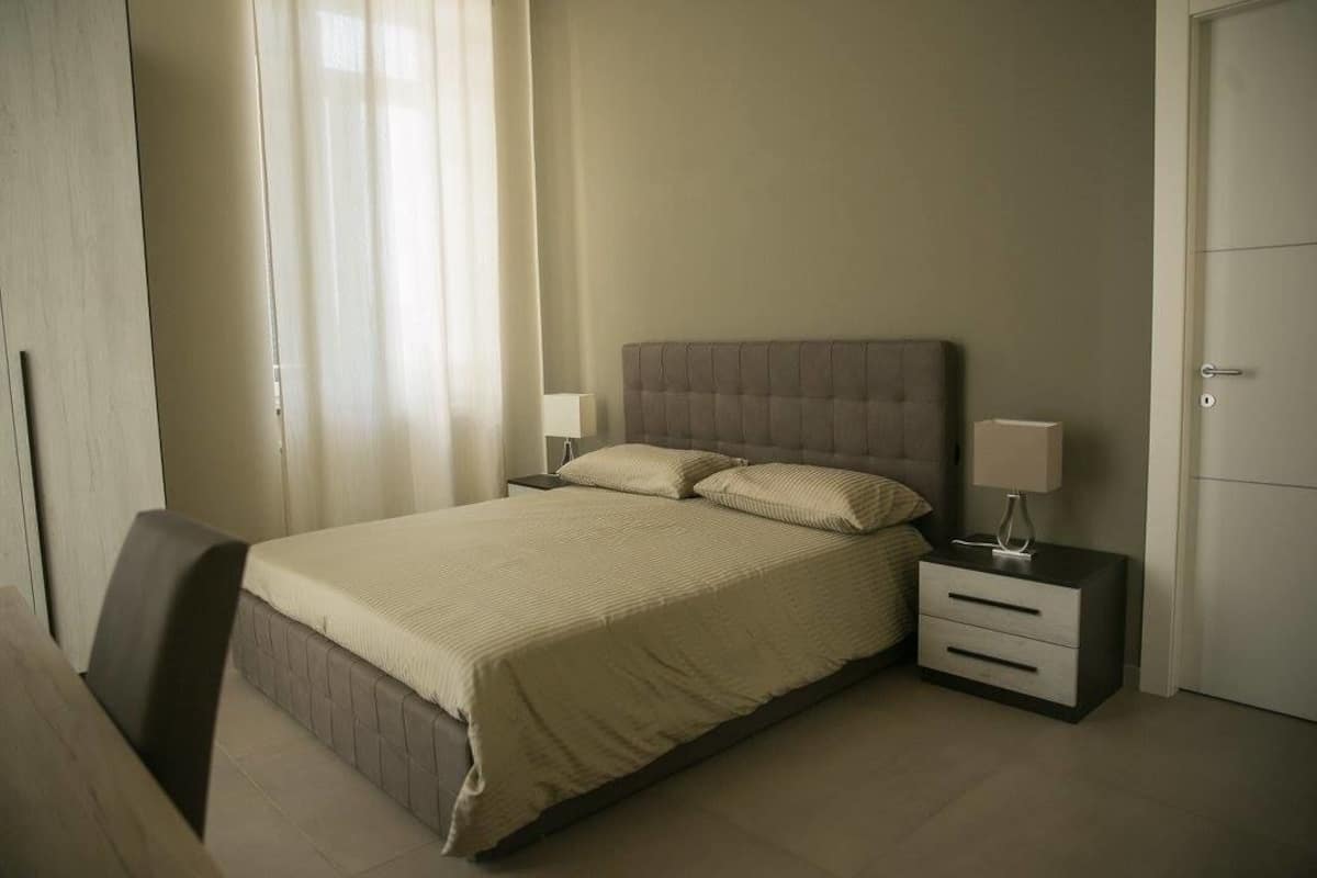 A bedroom with a bed, bedside tables, and a wardrobe.