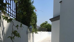 A narrow alleyway with a white wall on one side and a metal gate on the other. - Al Tartarughino B&B (Cercola)