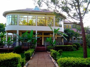 A two-story building with a curved facade, large windows, and a central entrance with steps. - Green Hills Lodge (Karatu)