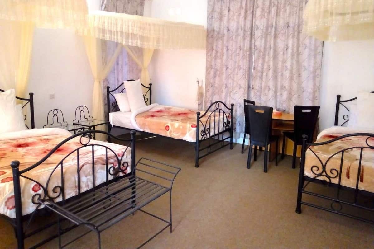 A room with three beds, a desk, and chairs.