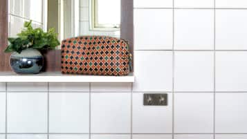 A bathroom with a white sink, a mirror with a wooden frame, and a patterned box on the countertop.