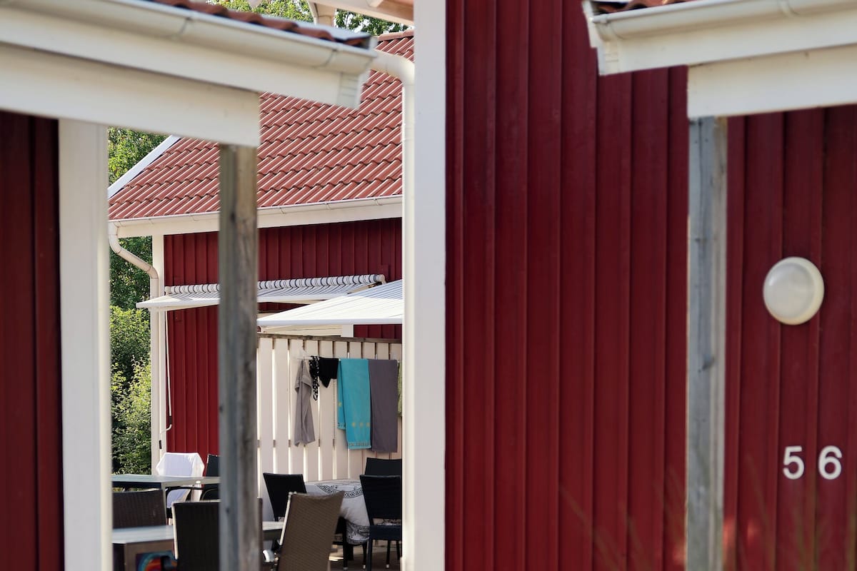 A red building with a number '56' on it, a covered outdoor seating area, and a paved walkway.
