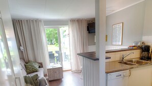 A compact kitchen with a dishwasher, a sink, and a small dining area with a table and chairs. - Apelviken Lägenhetshotell (Varberg)