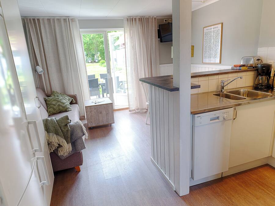 Una cocina moderna con lavavajillas, un lavaplatos y una zona de comedor con mesa y sillas.