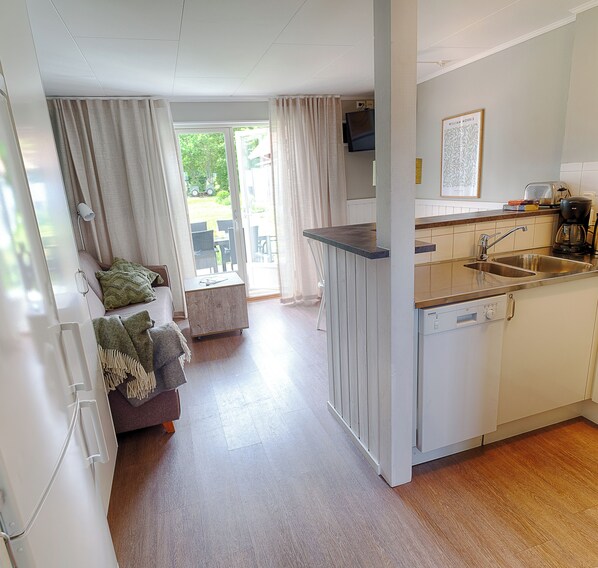 A compact kitchen with a dishwasher, a sink, and a small dining area with a table and chairs.
