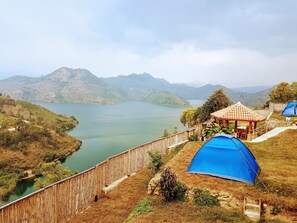 A camping area with a wooden fence, a gazebo, and a blue tent. - Macheo Ecolodge Camping (Bwishyura)