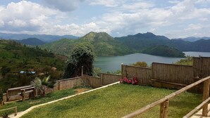 Vista de un paisaje montañoso con un lago, una valla de madera y una zona cubierta de hierba.
