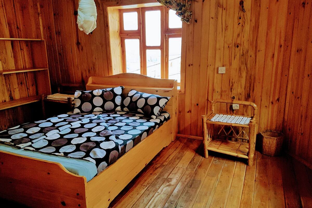 A wooden room with a bed, a chair, and a window.