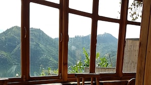 Interior rústico de madera con ventanas amplias que ofrecen vistas a colinas verdes.