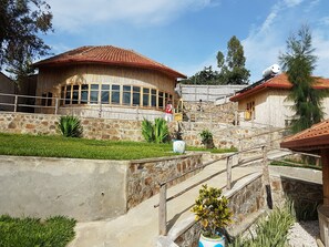 A building with a stone facade, a red-tiled roof, and a wooden staircase leading to a balcony.