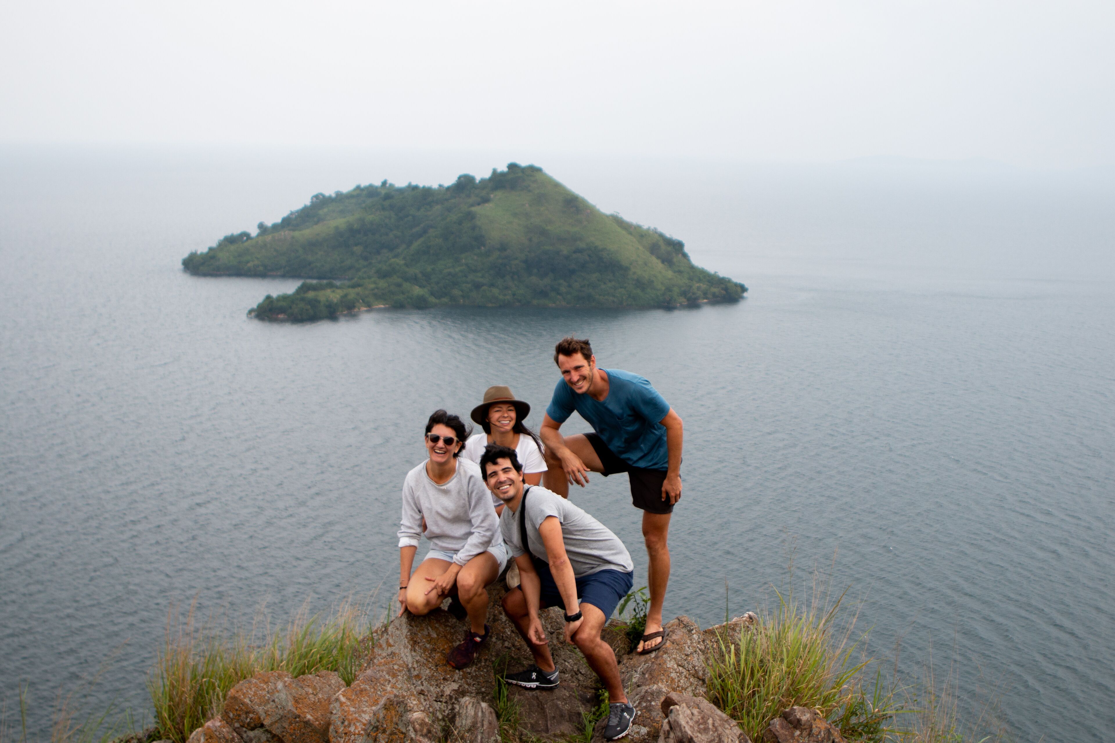 A group of people on a rocky outcrop overlooking a calm body of water with a small island in the distance.