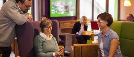 A modern lounge area with comfortable seating and a large screen displaying content.