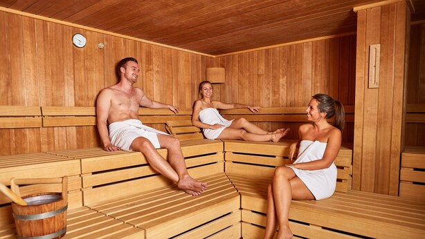 A sauna with wooden benches and a wooden bucket. - Explorer Hotel Ötztal (Umhausen)