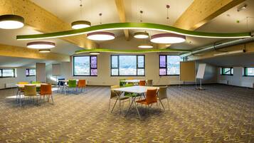 A spacious conference room with high ceilings, large windows, and modern lighting fixtures.