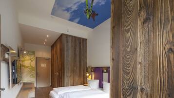 Habitación de hotel con una cama grande, armario de madera y un mural en el techo con un esquiador.