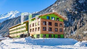 A hotel with a green and brown facade, multiple windows, and a sign reading "HOTEL". - Explorer Hotel Ötztal (Umhausen)