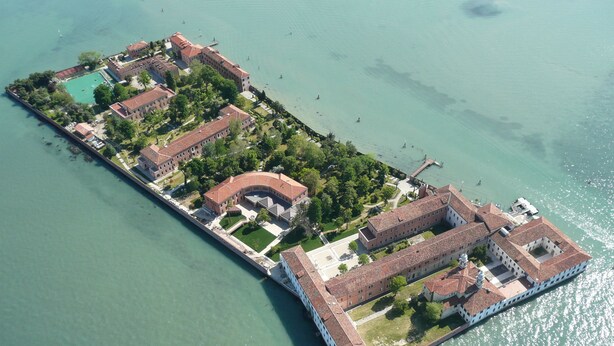 Vista aérea de una isla grande y rectangular con varios edificios, un patio central y una masa de agua que la rodea.