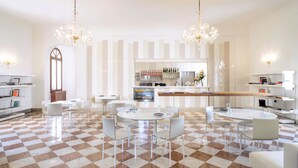 Un amplio vestíbulo de hotel con suelo de cuadros, muebles blancos y una zona de bar con botellas de vino.