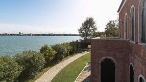 Vista al río con un edificio de ladrillo, un camino pavimentado y un árbol.