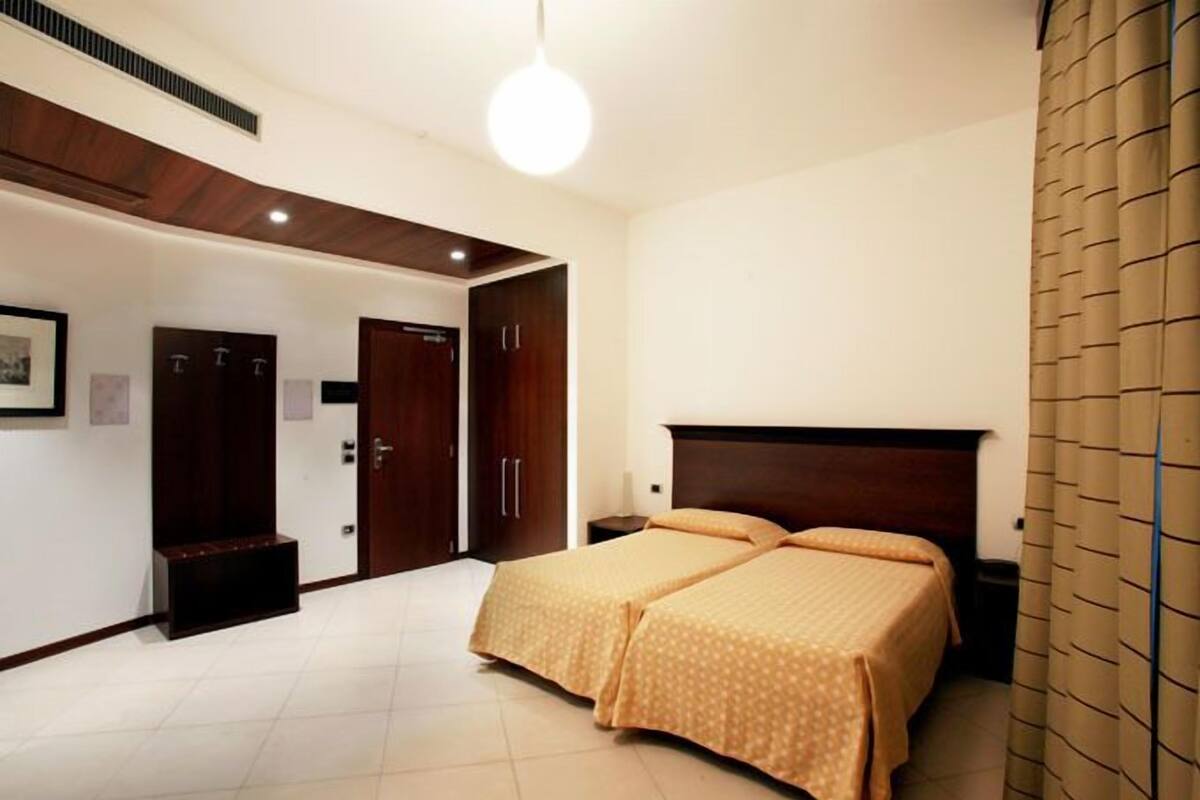 A bedroom with a large bed, a wardrobe, and a door leading to another room.