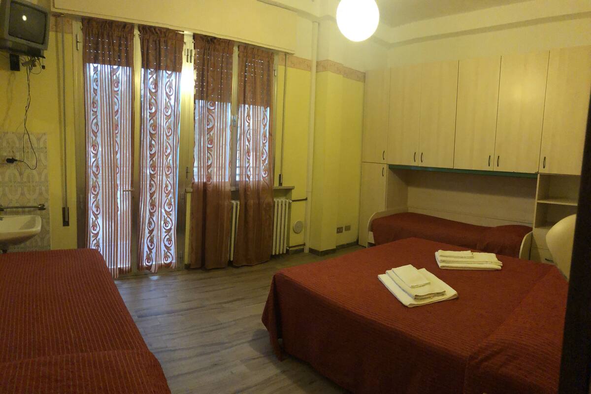 Une chambre d’hôtel avec deux lits, un lavabo, un radiateur et des rideaux.