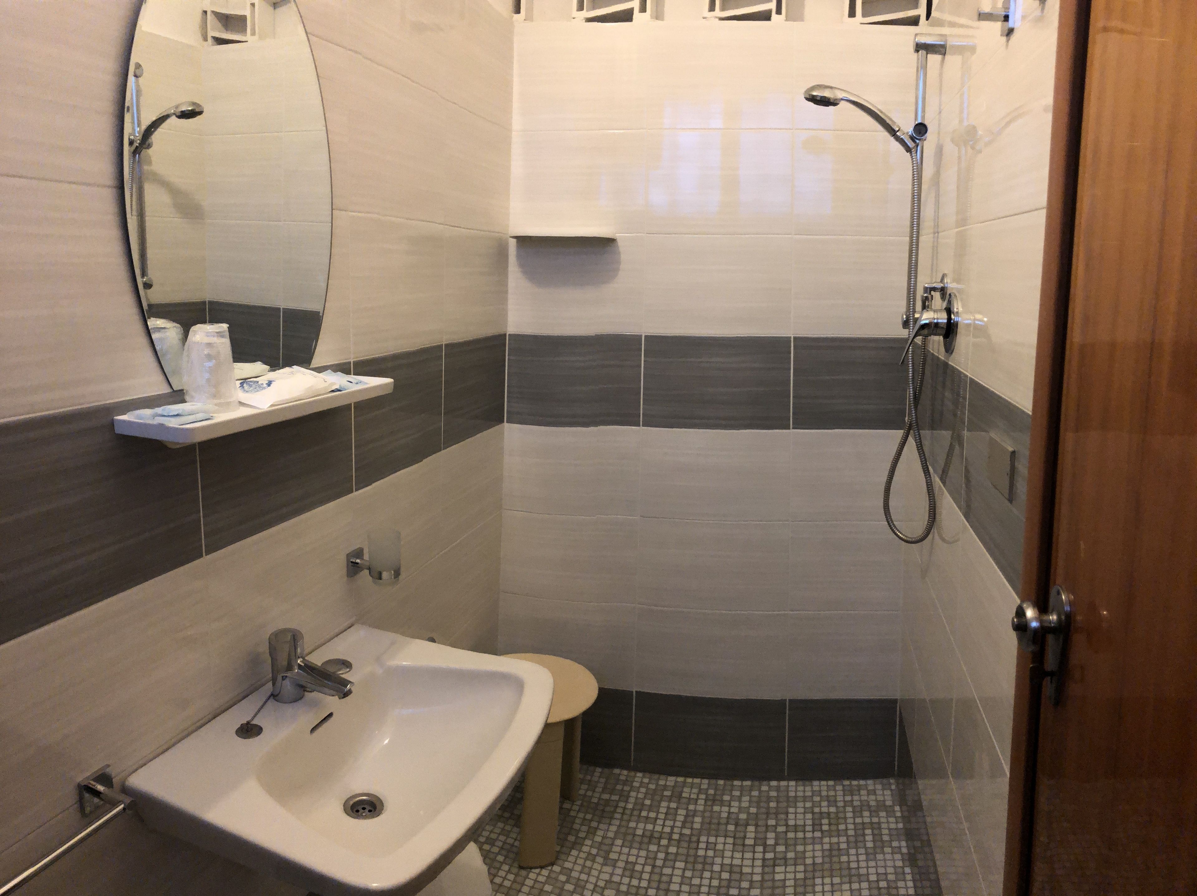Une salle de bain équipée d’un lavabo, d’un miroir, d’un porte-serviettes et d’une douche.