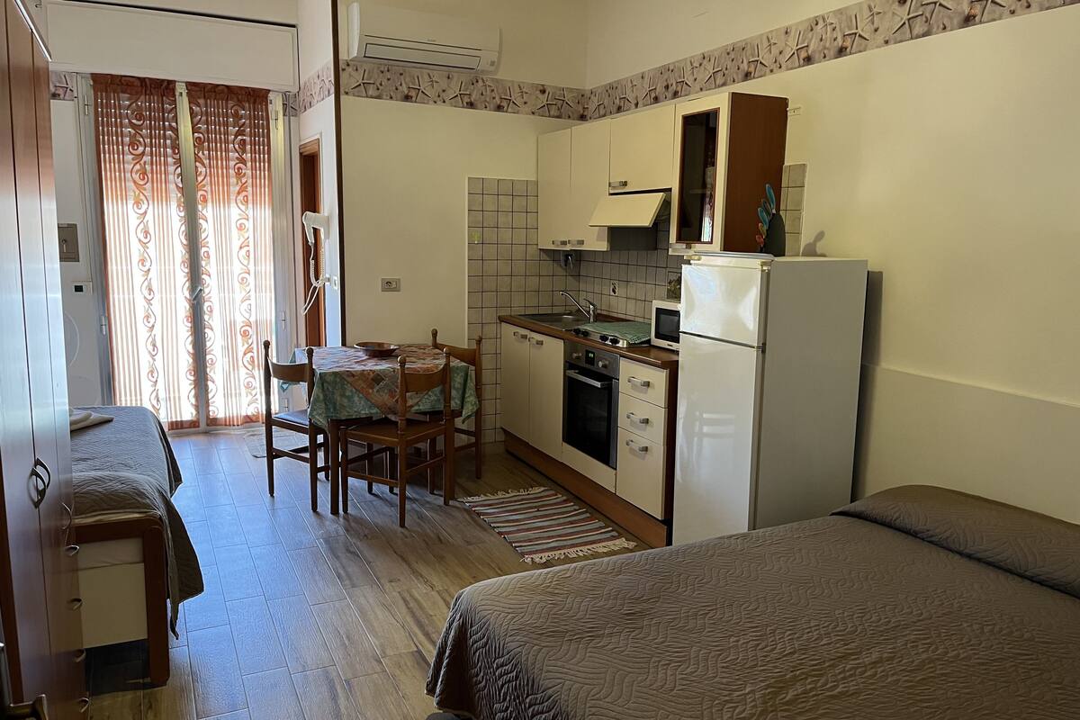 Une chambre d’hôtel compacte comprenant un coin cuisine, un espace repas et deux lits simples.