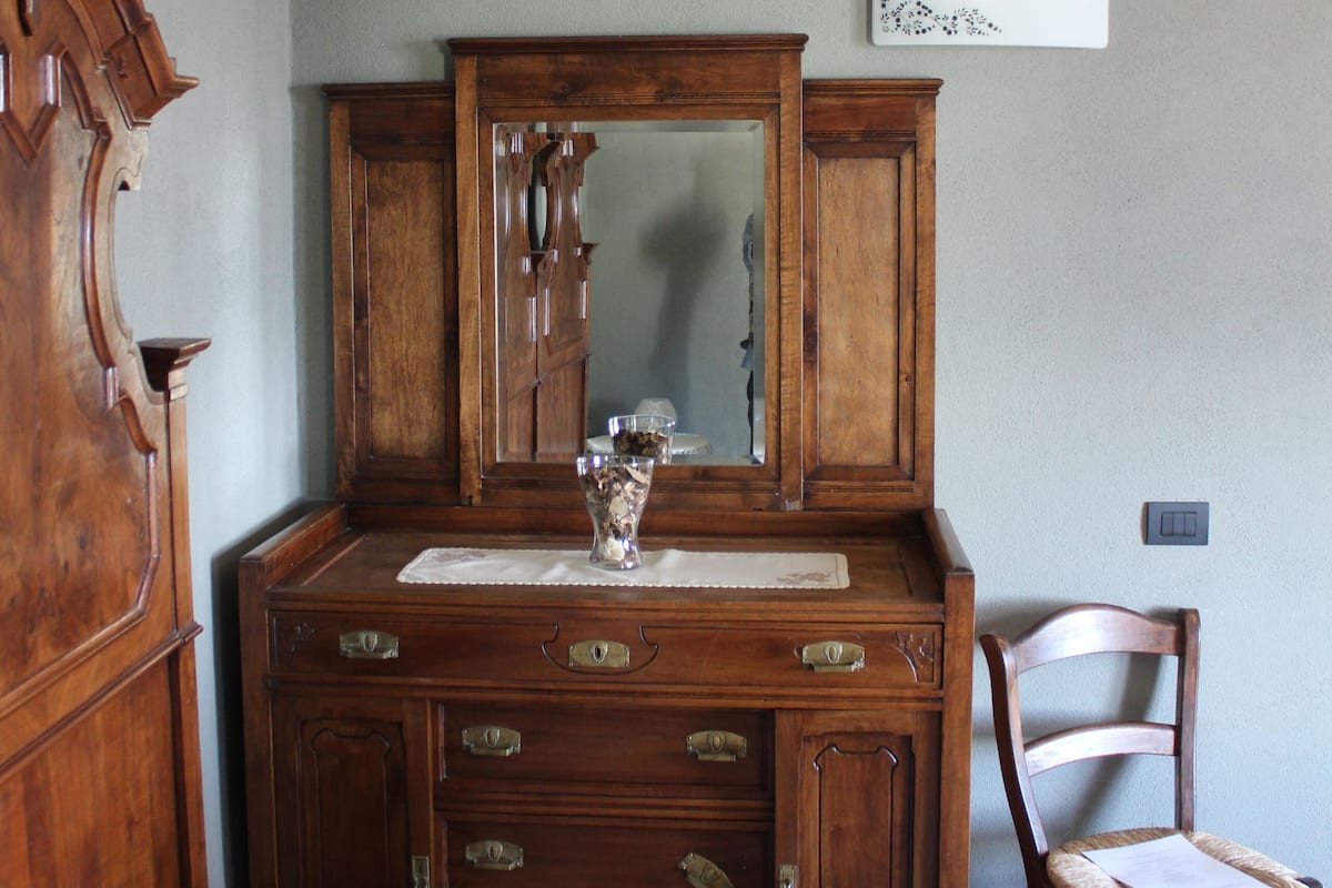 Un dormitorio con un aparador de madera, un espejo, una silla y una cama.