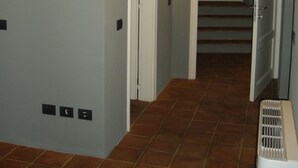Un pasillo con piso de baldosas, un respiradero en la pared y una puerta que da a otra habitación.