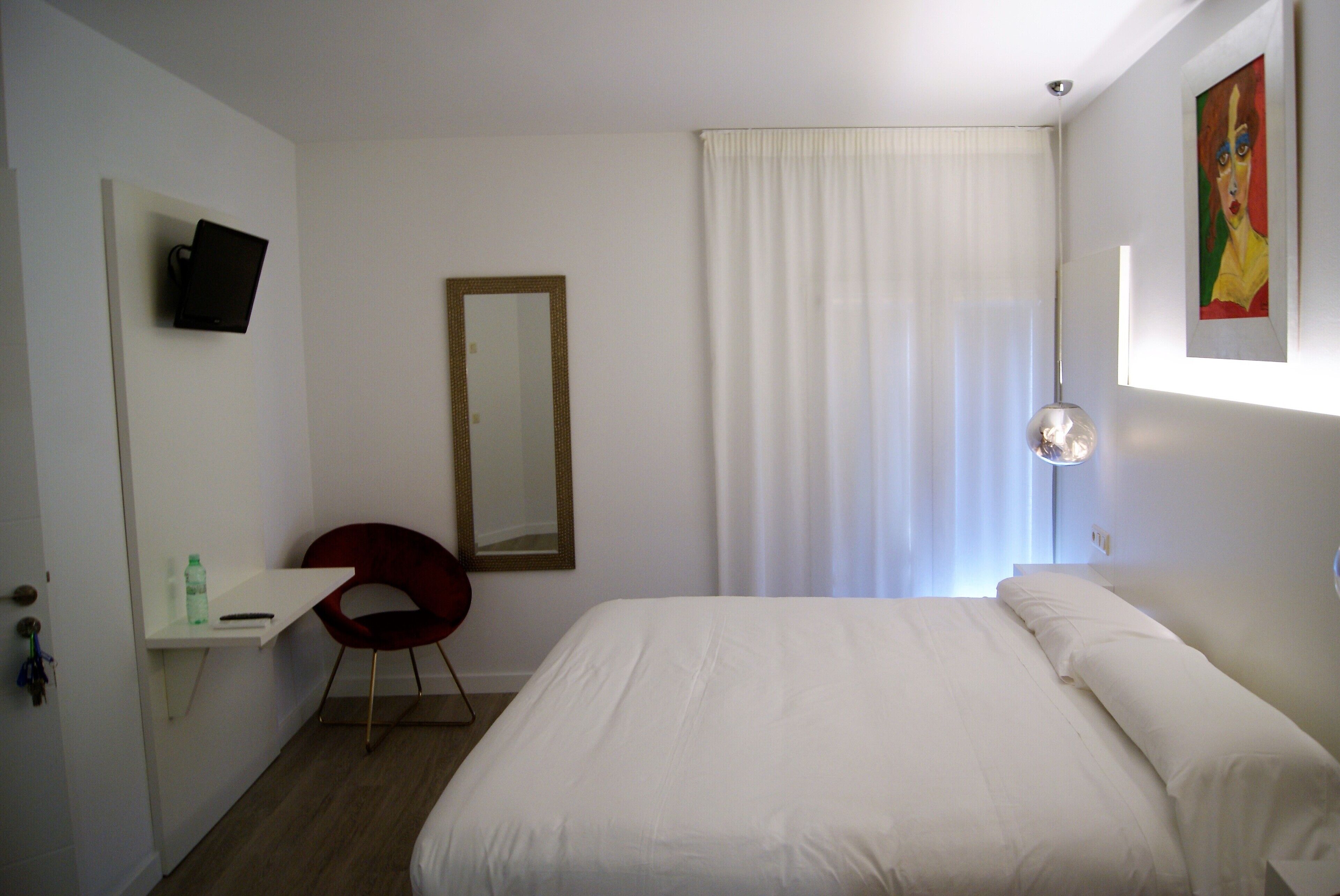 Een hotelkamer met een bed, een bureau, een stoel, een spiegel en een schilderij aan de muur.
