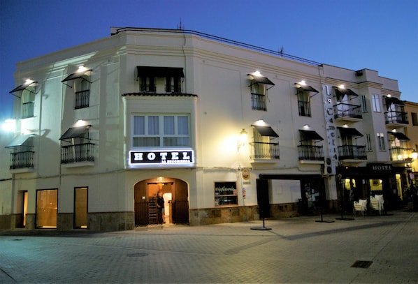 A hotel with a prominent 'HOTEL' sign, multiple balconies, and a well-lit entrance. - Hotel La Encomienda (Moraleja)