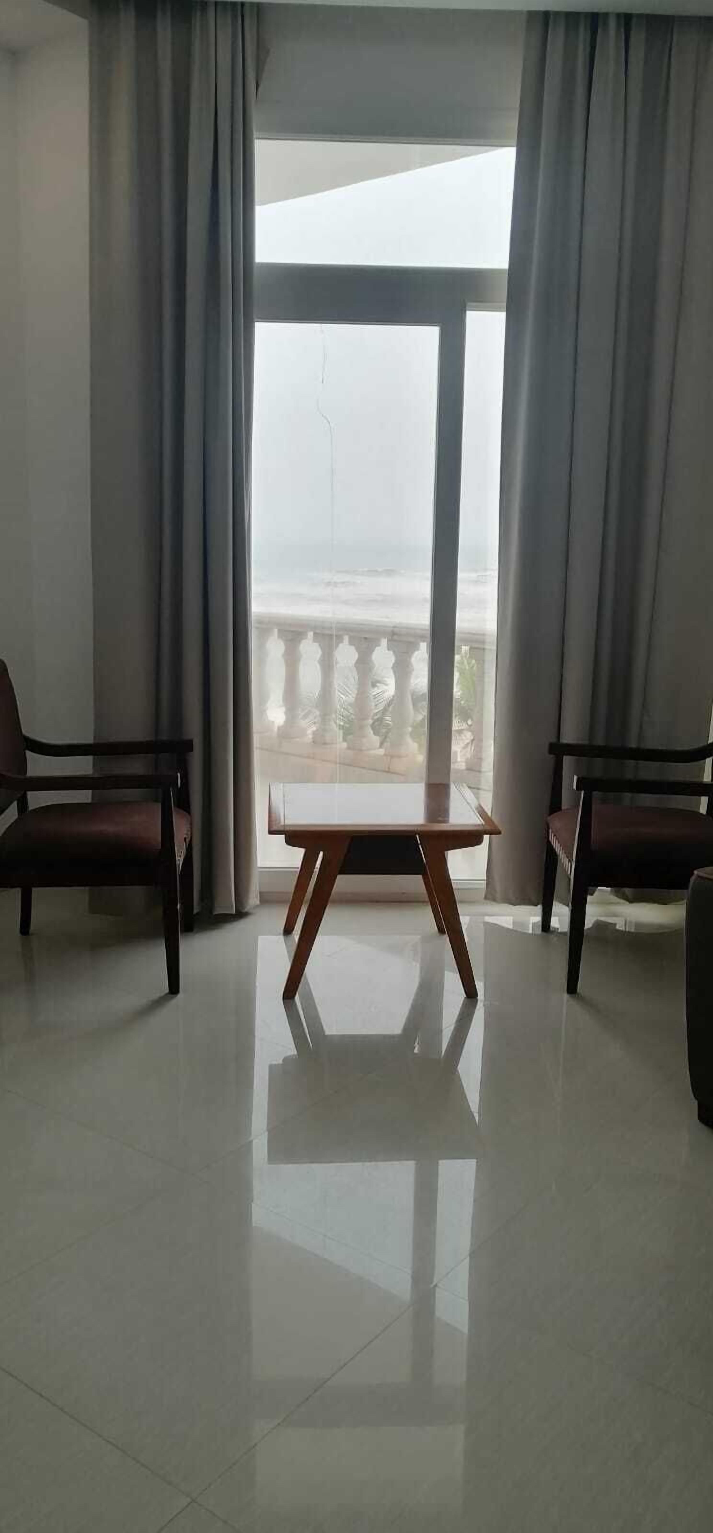 Una habitación con un ventanal grande, dos sillas y una mesa.