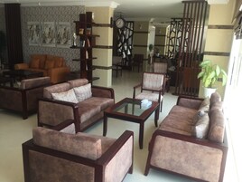 A spacious living area with multiple sofas and armchairs, a coffee table, and a bookshelf.