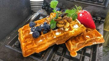 Una cialda ricoperta di mirtilli, fragole e noci, su una piastra per waffle.